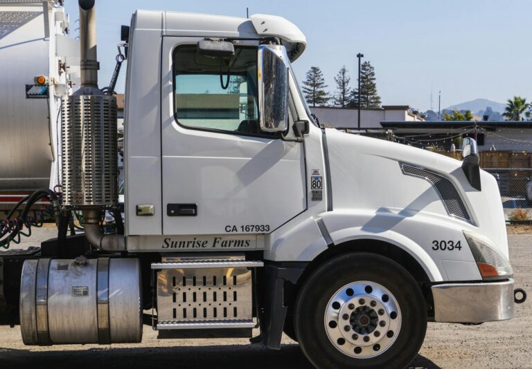 Side view of a white semi-trailer truck parked outdoors in an industrial area.